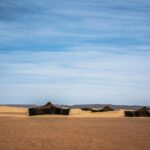 Majestic view of tents in the desert landscape of Zagora, Morocco with a clear blue sky.